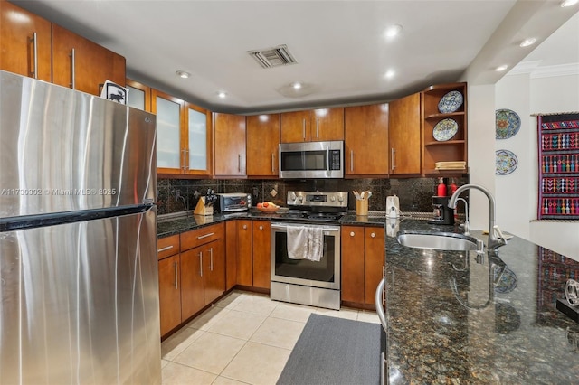 kitchen with tasteful backsplash, sink, dark stone counters, light tile patterned floors, and stainless steel appliances