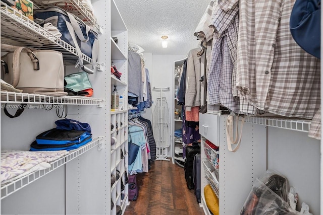 walk in closet with dark parquet flooring