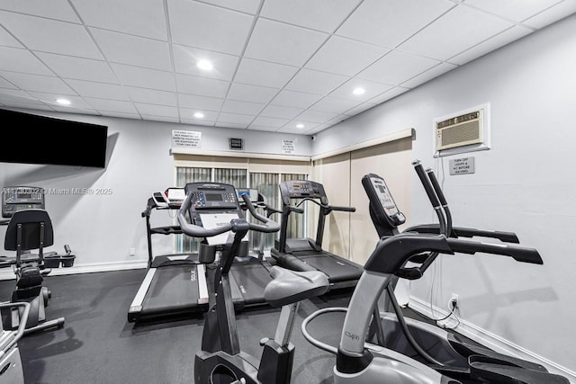 workout area featuring an AC wall unit and a drop ceiling