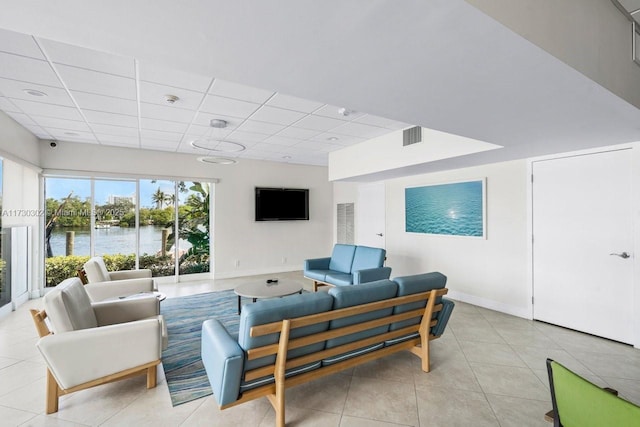 living room featuring a drop ceiling and light tile patterned floors