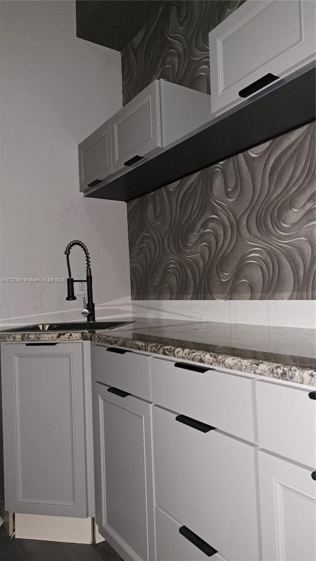 kitchen featuring sink, stone countertops, and white cabinets