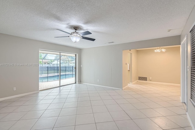 tiled empty room featuring ceiling fan with notable chandelier