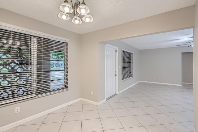 tiled empty room featuring ceiling fan with notable chandelier and a textured ceiling