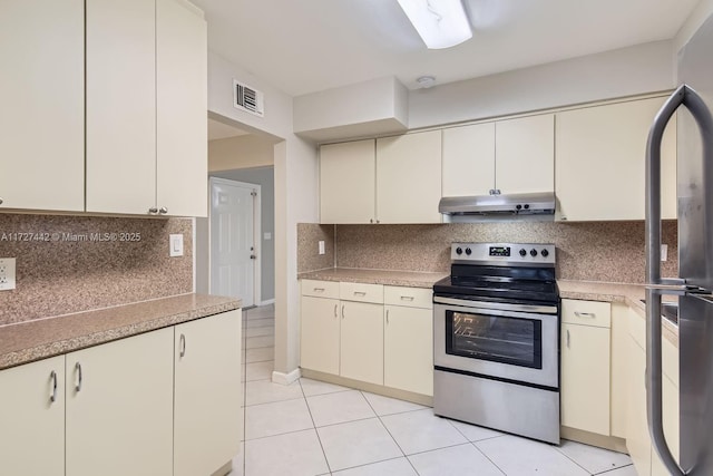 kitchen featuring black refrigerator, cream cabinetry, backsplash, light tile patterned floors, and electric range