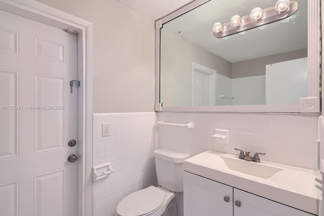 bathroom with vanity, toilet, and tile walls