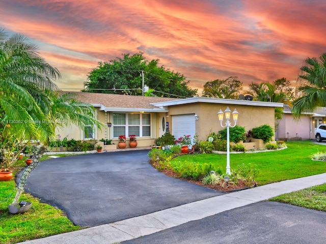 ranch-style home featuring a garage and a lawn