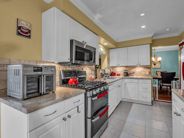 kitchen featuring decorative backsplash, white cabinets, appliances with stainless steel finishes, and sink