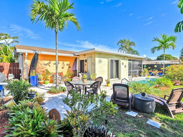 rear view of house featuring a fenced in pool, a sunroom, and a patio