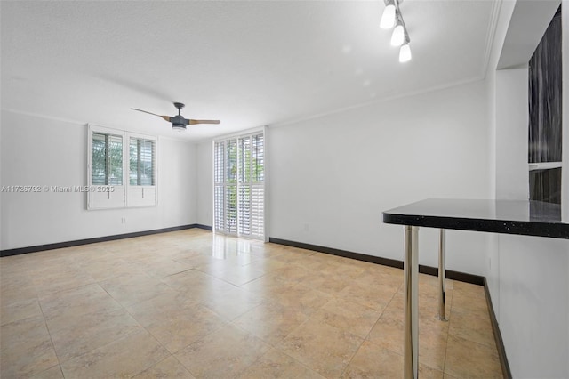 empty room featuring ceiling fan and ornamental molding