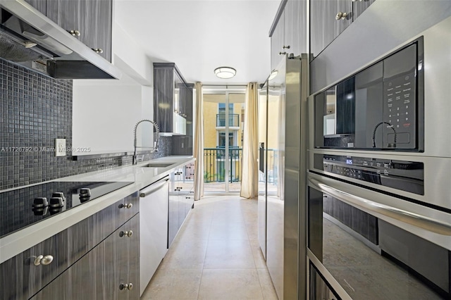 kitchen with black electric stovetop, sink, floor to ceiling windows, light tile patterned floors, and stainless steel dishwasher