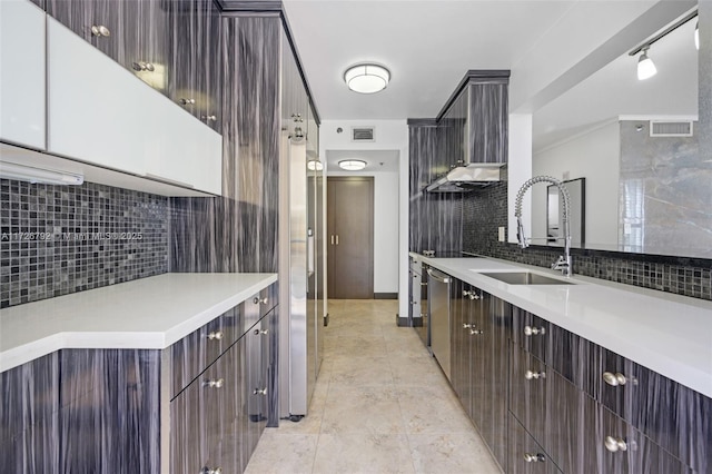 kitchen featuring stainless steel dishwasher, sink, backsplash, wall chimney range hood, and dark brown cabinetry