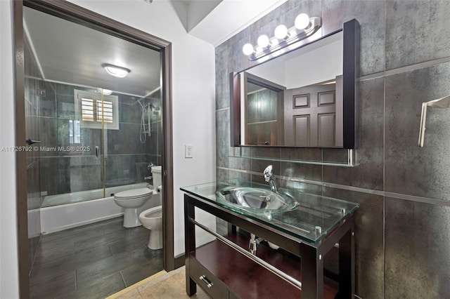 full bathroom with a bidet, toilet, tile walls, shower / bath combination with glass door, and vanity