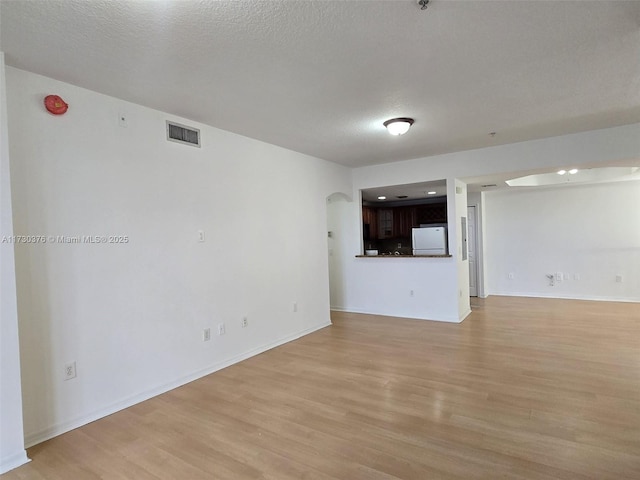 unfurnished living room with light wood-type flooring and a textured ceiling