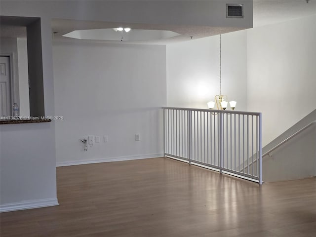 unfurnished room with a chandelier and hardwood / wood-style floors