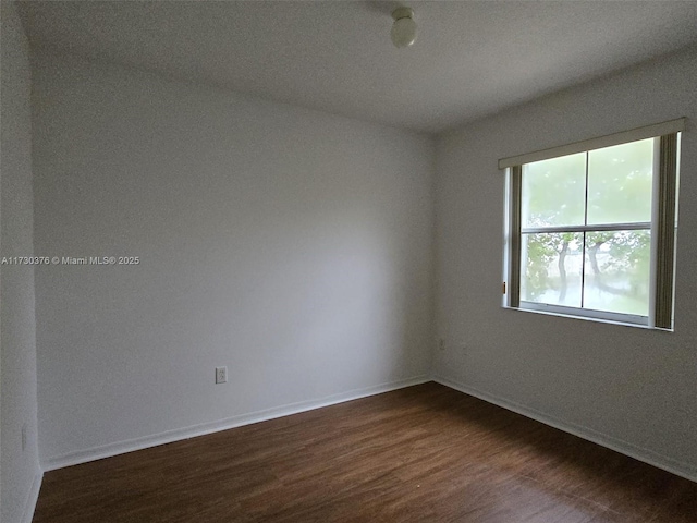 unfurnished room with dark hardwood / wood-style flooring