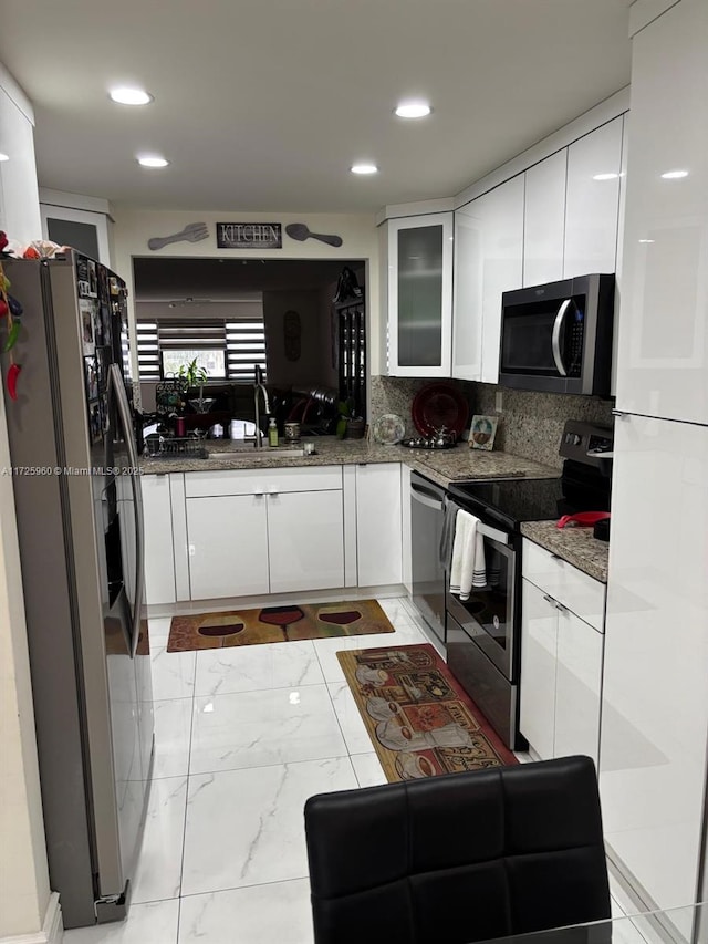 kitchen featuring sink, backsplash, white cabinets, and appliances with stainless steel finishes