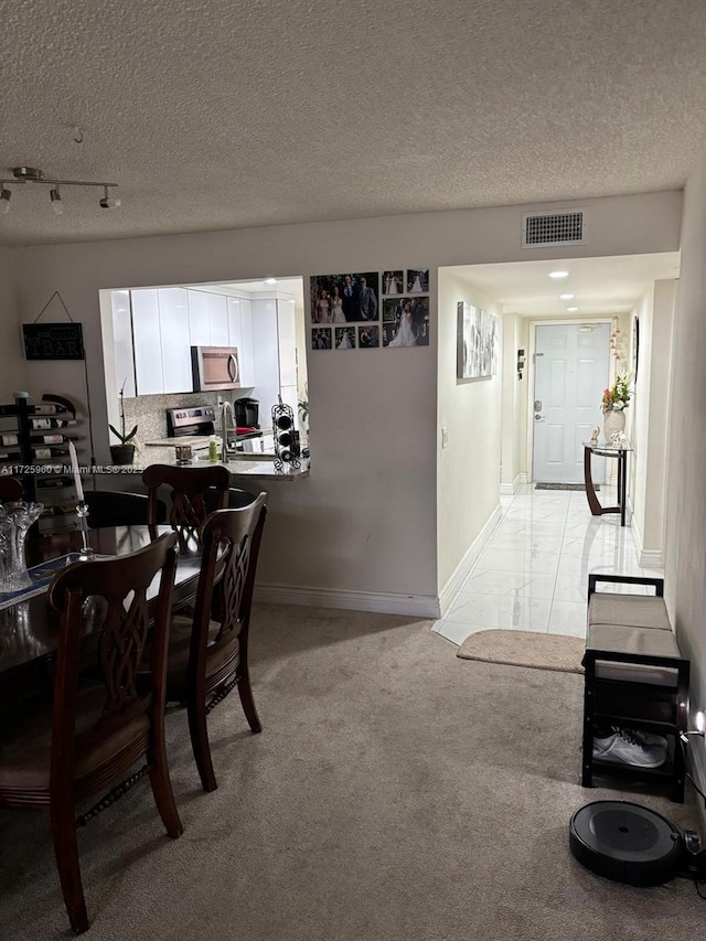 carpeted dining room featuring a textured ceiling