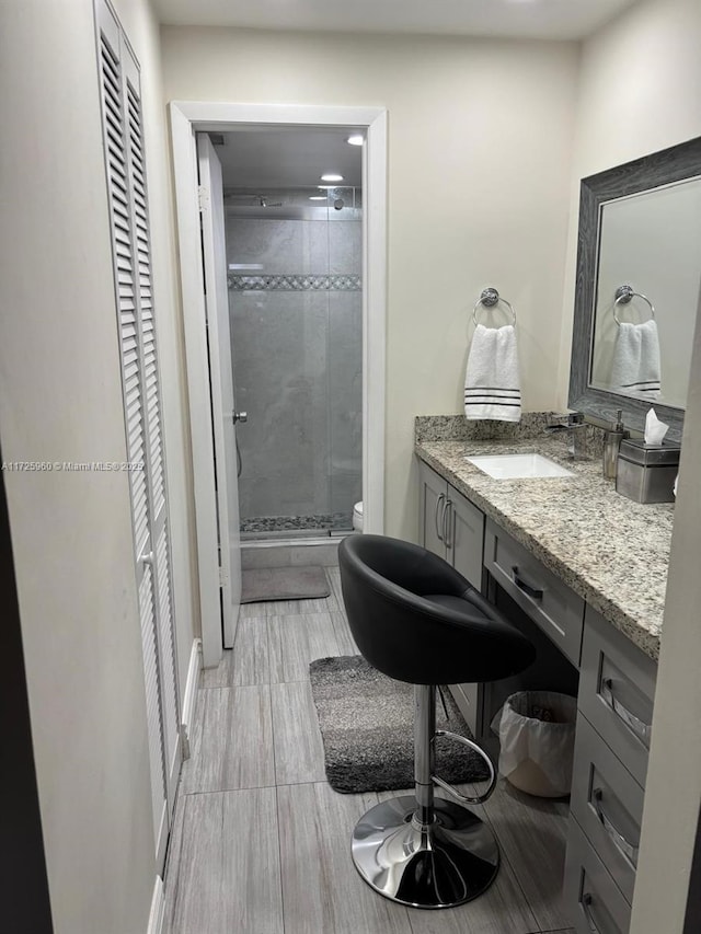 bathroom featuring vanity, a shower with shower door, and toilet