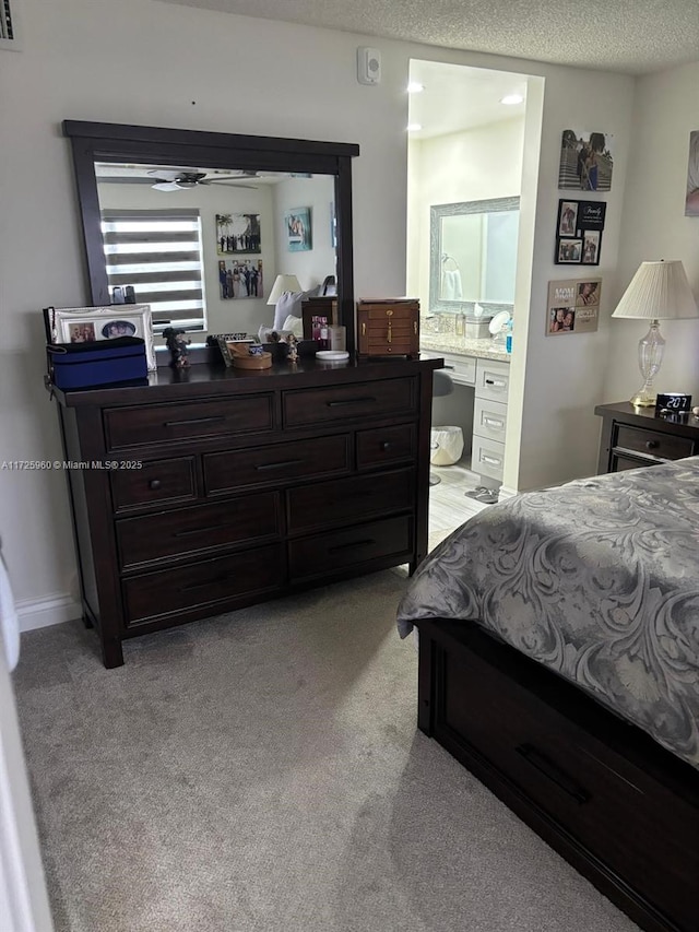 bedroom featuring light colored carpet, a textured ceiling, and ensuite bath