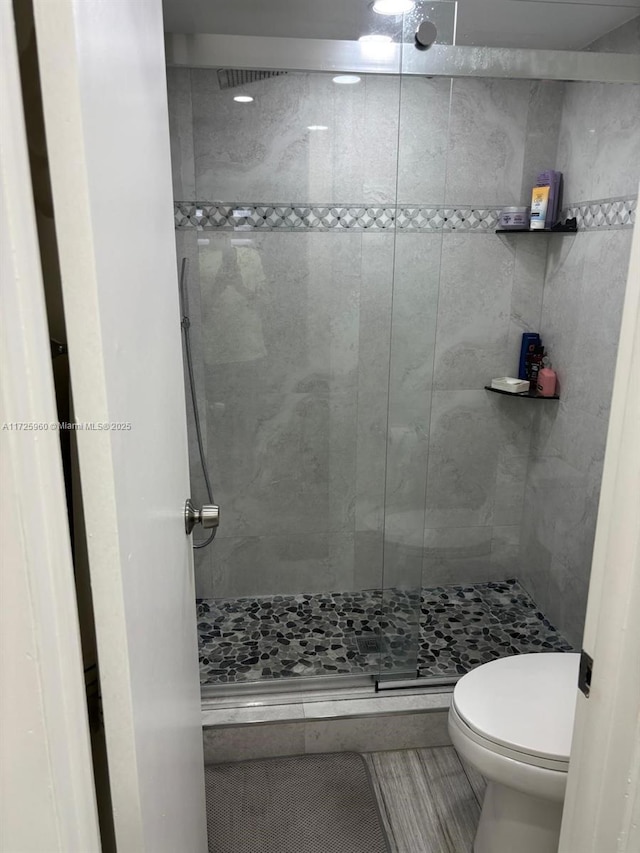 bathroom with toilet, tile patterned floors, and a tile shower