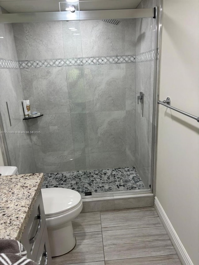 bathroom with vanity, a shower with shower door, and toilet