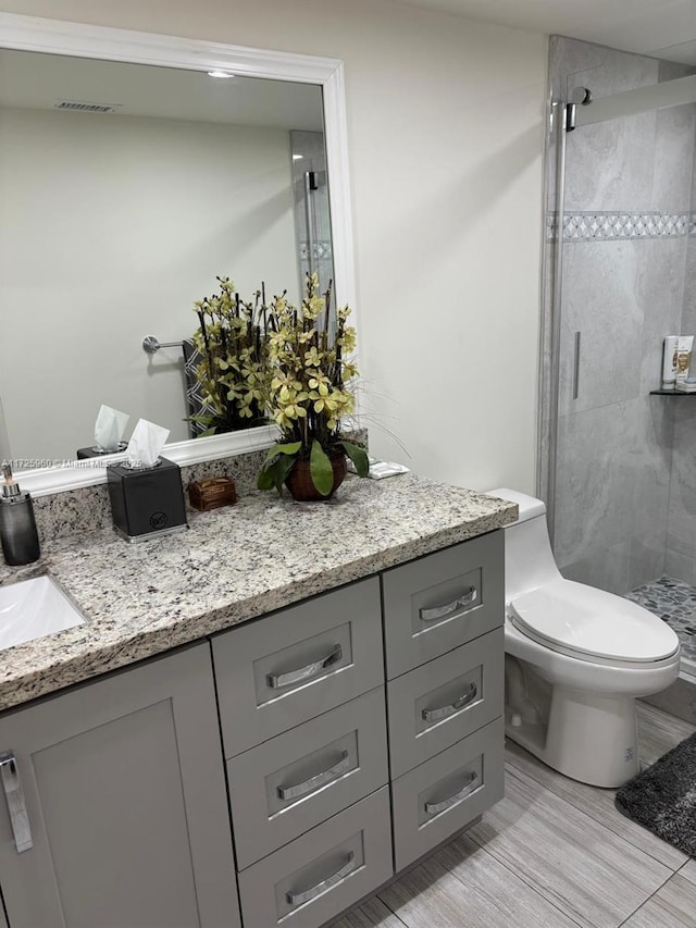 bathroom with hardwood / wood-style flooring, toilet, walk in shower, and vanity