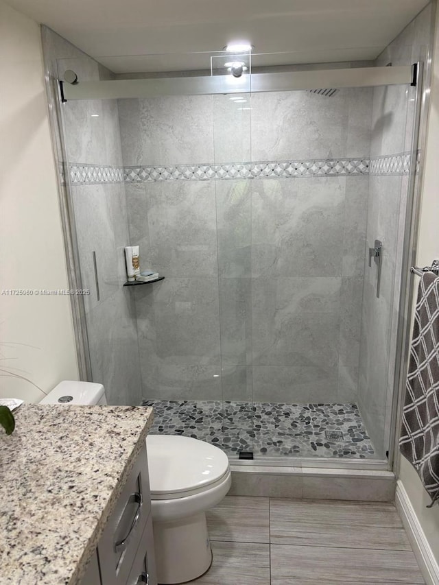 bathroom with a shower with shower door, toilet, vanity, and tile patterned flooring