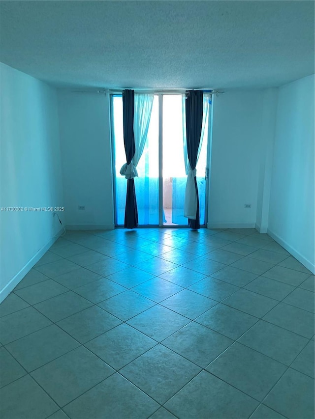 unfurnished room featuring a textured ceiling and light tile patterned floors