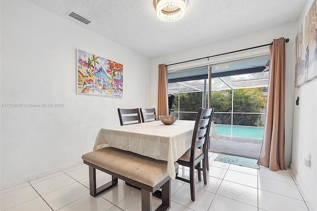 tiled dining room featuring a textured ceiling