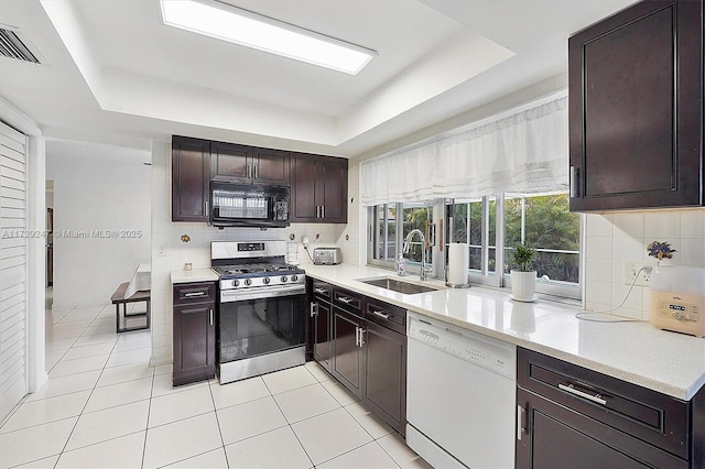 kitchen with dishwasher, sink, a raised ceiling, light tile patterned floors, and stainless steel range with gas stovetop