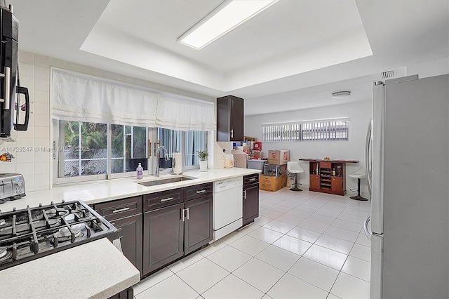 kitchen with dishwasher, a tray ceiling, and stainless steel refrigerator