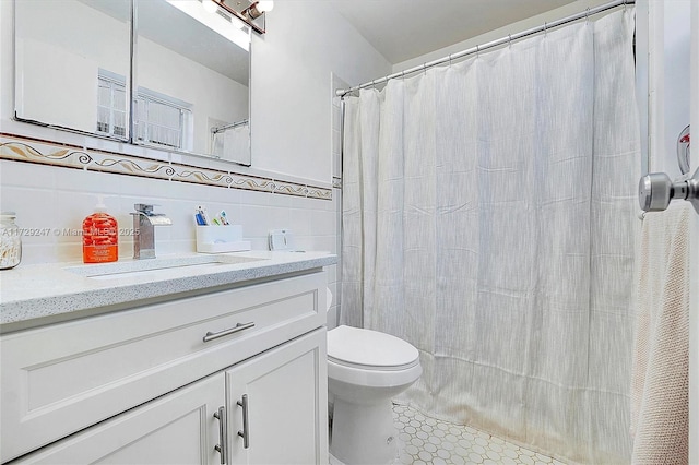 bathroom with tile patterned flooring, tile walls, toilet, vanity, and decorative backsplash