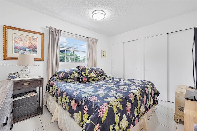 tiled bedroom featuring a textured ceiling and two closets