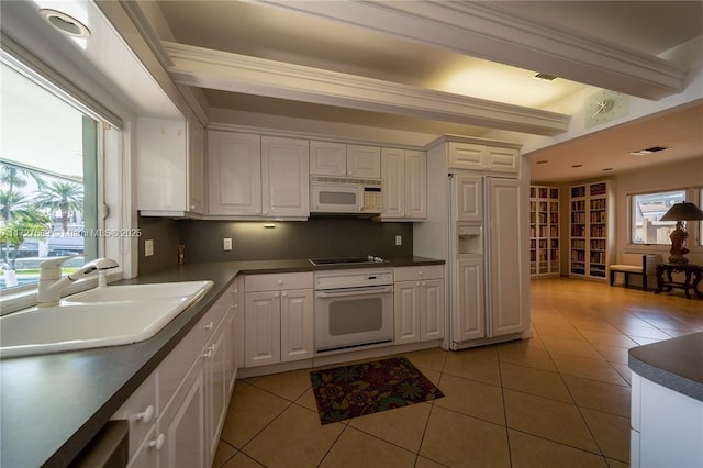 kitchen featuring sink, white cabinetry, white appliances, and light tile patterned floors