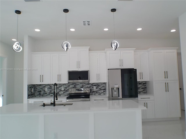 kitchen with decorative light fixtures, a center island with sink, white cabinetry, and stainless steel appliances