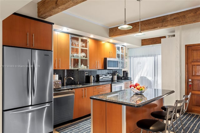 kitchen featuring sink, appliances with stainless steel finishes, a kitchen breakfast bar, a kitchen island, and backsplash