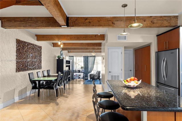 kitchen with pendant lighting, a breakfast bar area, stainless steel fridge, dark stone counters, and beam ceiling