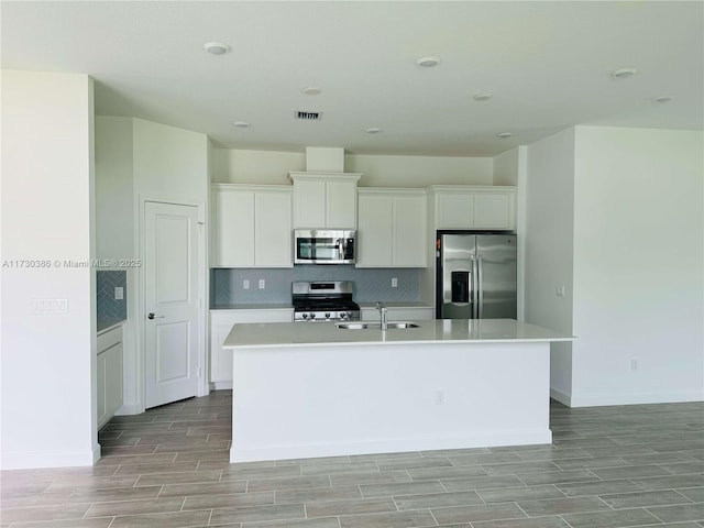 kitchen featuring sink, a center island with sink, white cabinetry, and stainless steel appliances