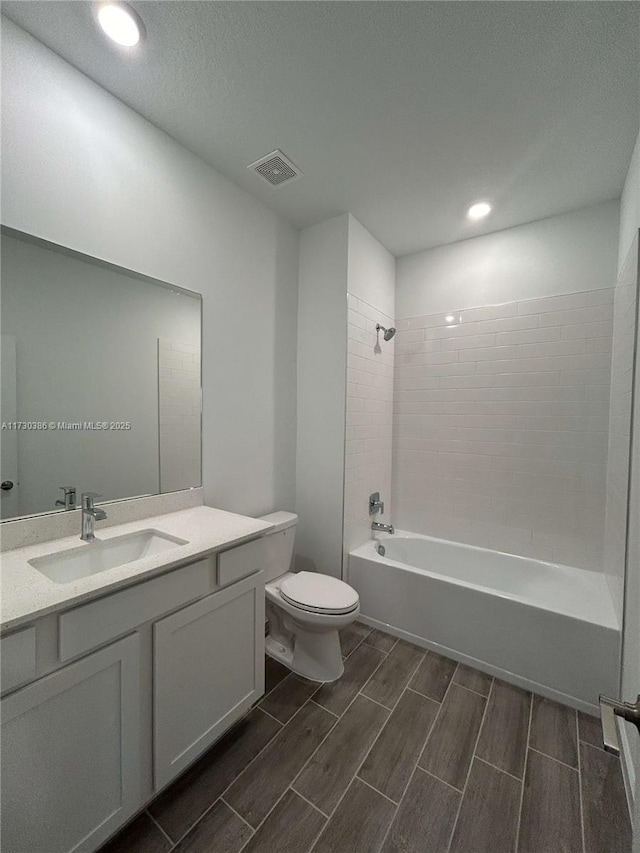 full bathroom featuring tiled shower / bath combo, vanity, and toilet