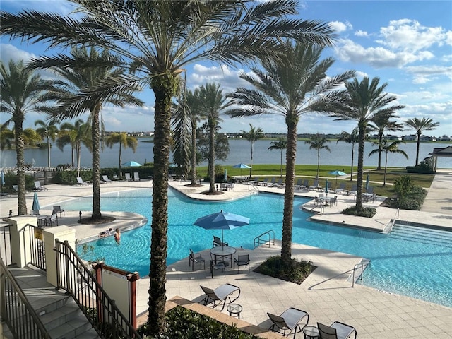 view of swimming pool featuring a water view and a patio area