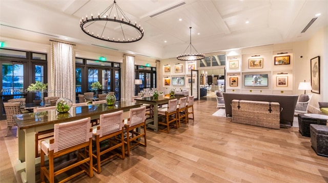 dining space with light hardwood / wood-style flooring, a chandelier, and coffered ceiling