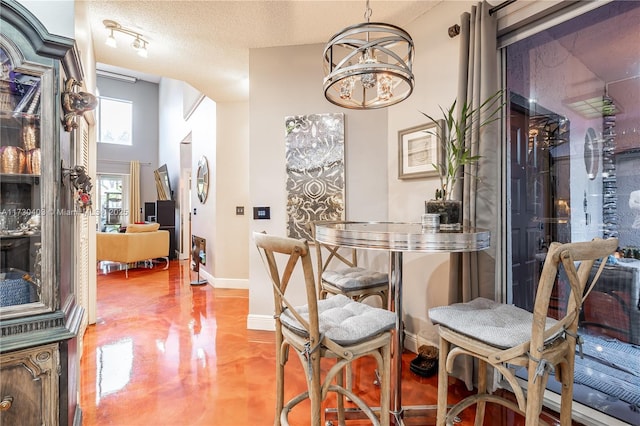 dining area featuring a textured ceiling, a notable chandelier, and concrete flooring