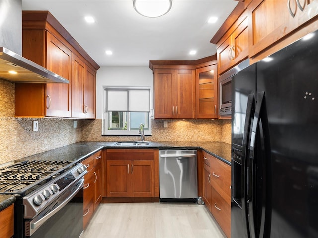 kitchen with wall chimney exhaust hood, sink, backsplash, dark stone counters, and stainless steel appliances