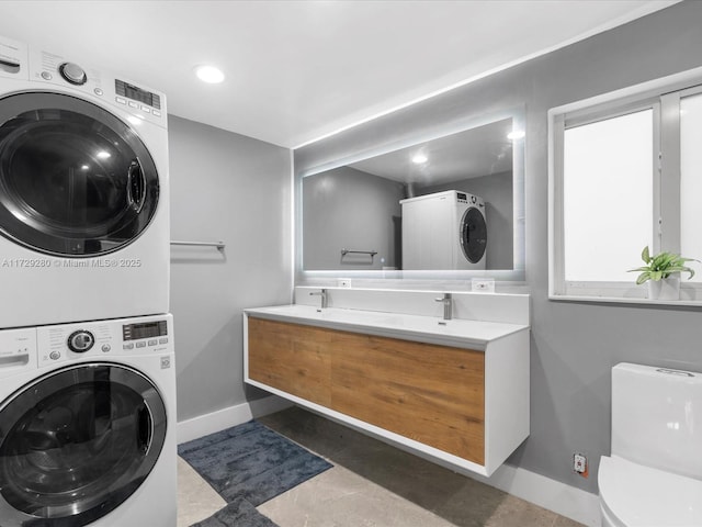 laundry room featuring stacked washer / drying machine and dark tile patterned floors