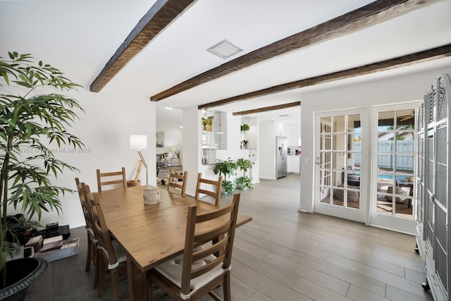 dining space with wood-type flooring and beamed ceiling