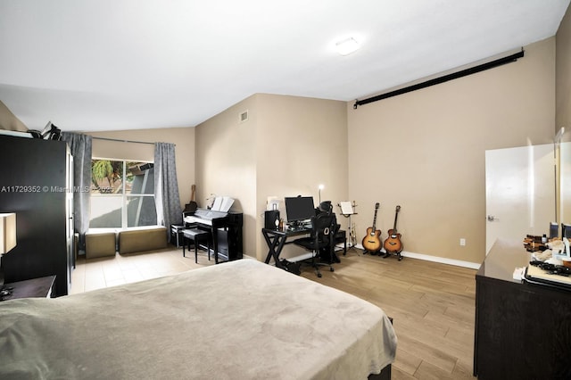 bedroom with light wood-type flooring and lofted ceiling