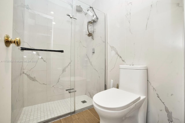 bathroom featuring toilet and a shower with door