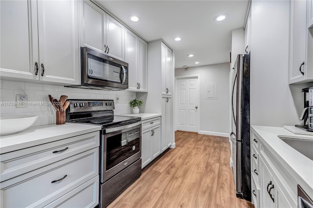 kitchen with white cabinets, stainless steel appliances, and light hardwood / wood-style flooring