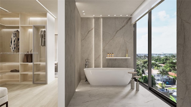 bathroom with a wall of windows, a tub, and plenty of natural light