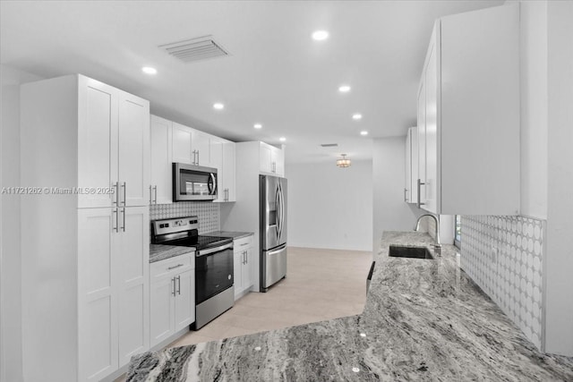 kitchen with sink, stainless steel appliances, white cabinetry, and light stone countertops